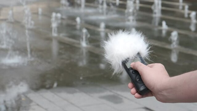 Voice recorder in hand. Recording sound effects, voice level, Noise control. Sounds of urban life.