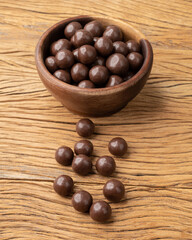 Obraz premium Chocolate malted balls on a bowl over wooden table