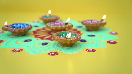 Oil lamps lit on colorful rangoli during diwali celebration. Happy Diwali - Clay Diya lamps lit...