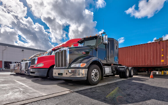 Lined up Semi truck heads on a parking lot at logistics warehouse.