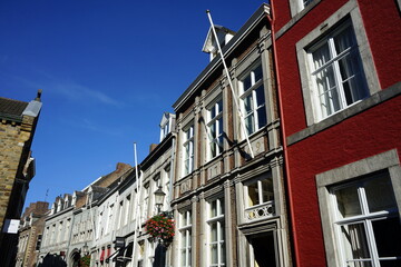 Häuserzeile mit restaurierten Altbauten in der Stokstraat vor blauem Himmel im Sonnenschein in der Altstadt von Maastricht an der Maas in der Provinz Limburg der Niederlande - obrazy, fototapety, plakaty
