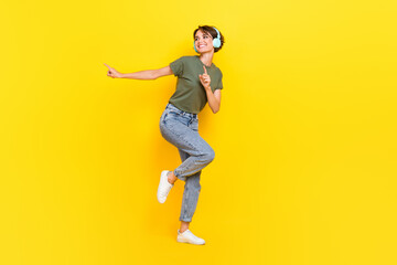 Fototapeta na wymiar Full length photo of funny funky lady look empty space wear earbuds listen playlist enjoy sound isolated on yellow color background
