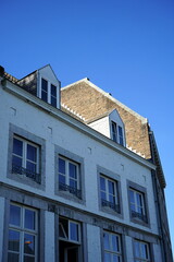 Sanierter Altbau mit Dachgaube vor alter Brandmauer im Sonnenschein vor blauem Himmel im...
