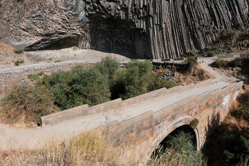 View of medieval bridge in Basalt canyon of Azat river on sunny day. Garni village, Armenia.