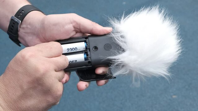 Voice recorder in hand. Replacing the batteries in device. Recording sound effects, voice level, Noise control. Sounds of urban life.