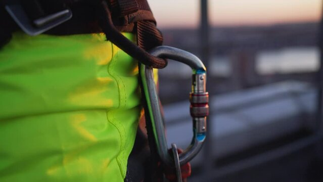 Close-up of a male climber snapping a carabiner onto the unloading loop of the safety system