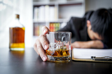 Glasses of whiskey in businessman's hands on wooden table background