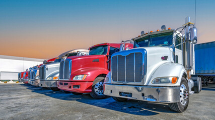 Lined up Semi truck heads on a parking lot at logistics warehouse.