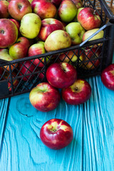 A bunch of red apples in a crate on a turquoise wooden background