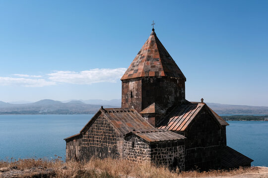 View of Surp Arakelots (Holy Apostles) church of Sevanavank monastery and Sevan lake on sunny summer day. Gegharkunik Province, Armenia.