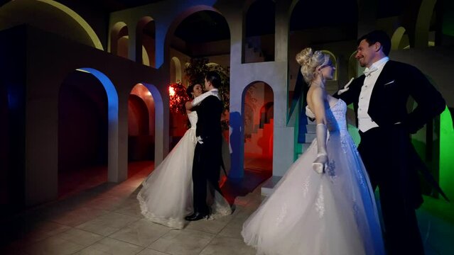 two dancing couples are whirling in fabulous ballroom, professional dancers in royal ball