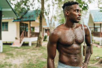Black young sportsman resting while working out with jumping rope outdoors