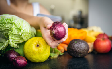 Close-up, onion in female hands on a blurred background of the kitchen.