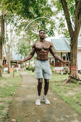 Black young sportsman working out with jumping rope outdoors