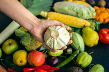 Close-up, cabbage in a woman's hand on the kitchen table among vegetables.