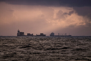 Commercial ships against dramatic cloudy sky with sunbeams