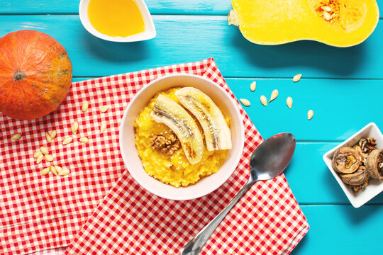 Rice milk pumpkin porridge with walnuts, butter and honey on a blue wooden table. Healthy food.