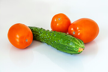 fresh juicy cucumber and tomatoes for salad on white glass surface