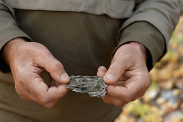 Natural unprocessed pieces of mica minerals in the hands of a man in a natural deposit.