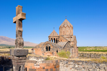 View of stone column with cross and Hovhannavank monastery on sunny summer day. Ohanavan, Armenia.