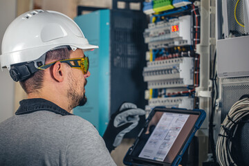 Man, an electrical technician working in a switchboard with fuses.
