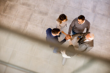 Business people team stack hands as unity gesture in the office hallway