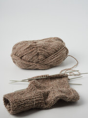 Fototapeta na wymiar Brown socks hand made of sheep wool. Top view photo of knitted socks, needles and ball of warm yarn. Winter hobbies concept.