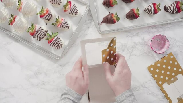 Time lapse. Flat lay. Step by step. Packaging chocolate dipped strawberries into a paper box for a gift.