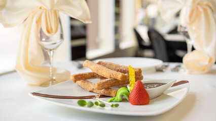 Beautiful served dessert food on plate. Churros with chocolate and candy strawberry