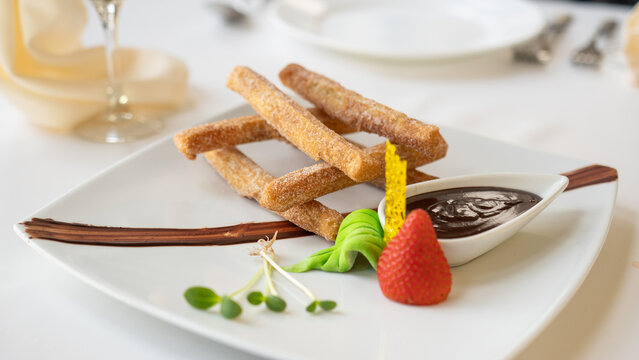Beautiful served dessert food on plate. Churros with chocolate and candy strawberry