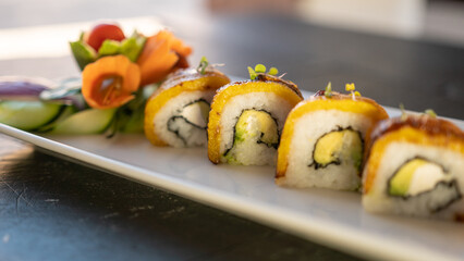 Beautiful served vegetarian sushi rolls on a plate. With natural vegetables and sauce. Black background