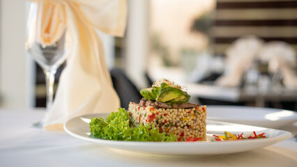 Beautiful served sago with meat, avocado and green lettuce leaves on plate. Shabbat food. Restaurant on a background.