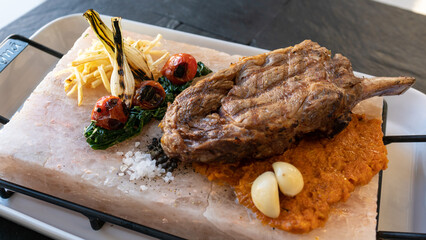 Delicious steak on the salt stone with grilled vegetables, potato and sous. Restaurant background, kosher
