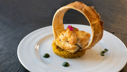 beautifully served fish in cream sauce with rice. a glass of white wine and restaurant background