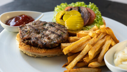 Tasty burger with beef, tomatoes, onion, pickles, and french fries. Restaurant background. 