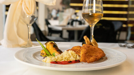breaded fried chicken breast with vegetables, mashed potatoes and green leaves. black background