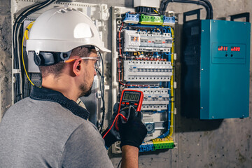 Man, an electrical technician working in a switchboard with fuses.