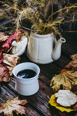Tasse de café expresso en grès blanc et arrière plan avec des feuilles d'automne et un bouquet...