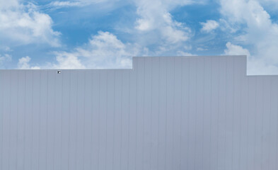 Side facade of a large big box style building, white vertical aluminum siding, daytime, cloudy sky above, nobody