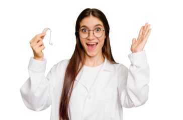 Young otorhinolaryngologist caucasian woman holding hearing aid isolated receiving a pleasant surprise, excited and raising hands.