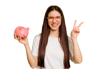 Young caucasian woman holding a piggy bank isolated joyful and carefree showing a peace symbol with fingers.
