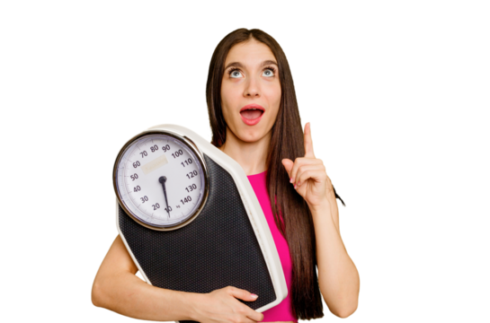 Young caucasian woman holding a scale isolated pointing upside with opened mouth.