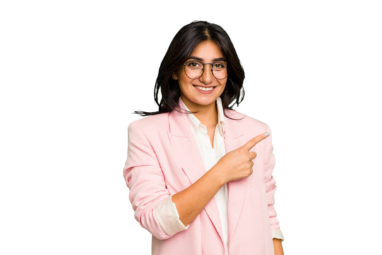 Young Indian business woman wearing a pink suit isolated smiling and pointing aside, showing something at blank space.