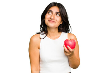 Young Indian woman holding an apple, healthy lifestyle, isolated dreaming of achieving goals and...