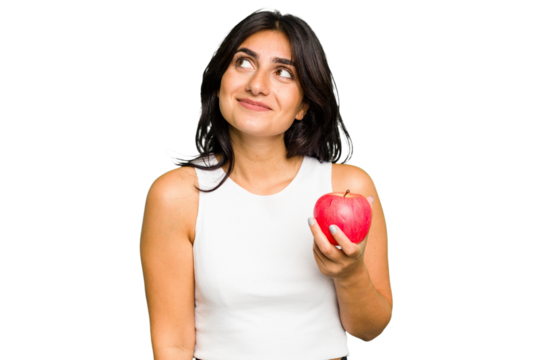 Young Indian woman holding an apple, healthy lifestyle, isolated dreaming of achieving goals and purposes