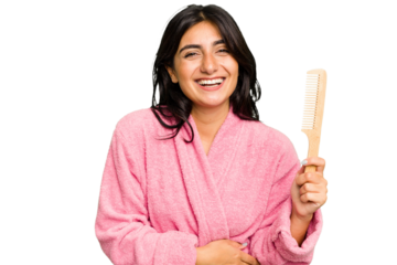 Young woman in a bathrobe holding an hair comb isolated laughing and having fun.