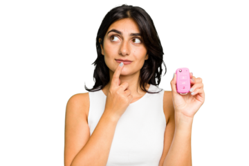 Young Indian woman holding a car keys isolated relaxed thinking about something looking at a copy space.