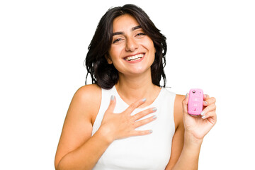 Young Indian woman holding a car keys isolated laughs out loudly keeping hand on chest.