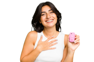 Young Indian woman holding a car keys isolated laughs out loudly keeping hand on chest.