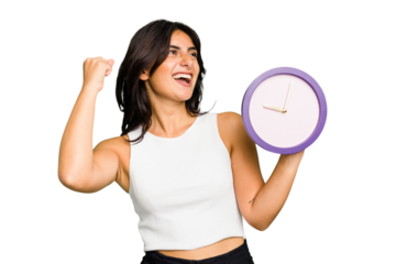 Young Indian woman holding a clock isolated raising fist after a victory, winner concept.